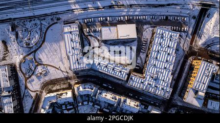 Panorama aerial top down residential complex after a snow storm with Ettegerpark seen from above with roof full of solar panels covered in white Stock Photo