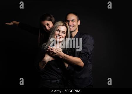 Happy young family with one child having fun together isolated on black. Stock Photo