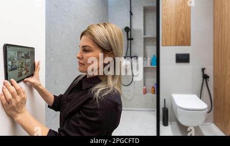 Woman using smart wall home control system Stock Photo