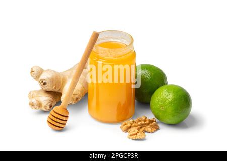 Honey in an open jar with nuts, lime and ginger on a white background. Healthy foods. Honey in a glass jar with honey stick on isolation Stock Photo