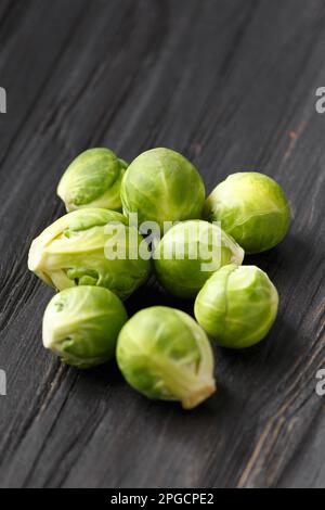 A handful of Brussels sprouts on a wooden background. Fresh cabbage on a dark background. Products for vegans. Useful vegetables. Diet for vegetarians Stock Photo