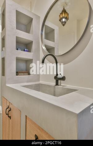 Interior design of contemporary bathroom with granite gray sink and black faucet on wooden cabinets under round mirror Stock Photo