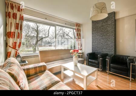 Spacious modern living room with comfortable sofas and small table placed on wooden floor against big window Stock Photo