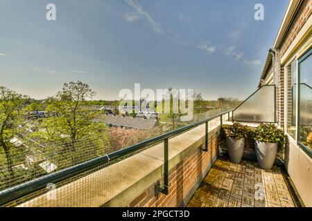 Exterior view of balcony with green potted plants with glass windows reflecting countryside trees in sunlight Stock Photo
