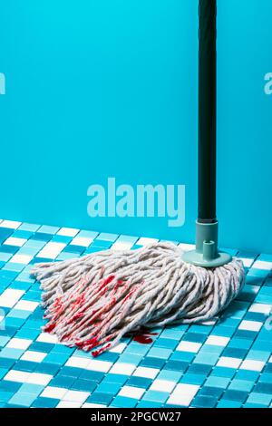 Wash mop with blood spots on blue and white mosaic tile placed against blue wall Stock Photo