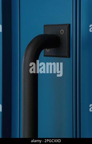 Large black matte metal handle on a blue door close up Stock Photo