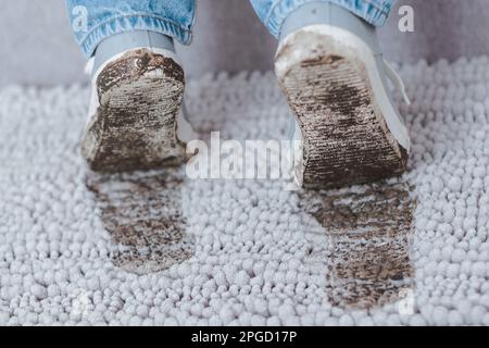 Muddy footprint on gray carpet. Dirty shoes with mud and soil. Daily life dirty stain. Stock Photo