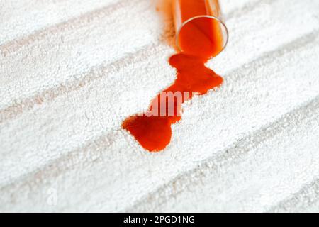 Pouring red juice a glass on a white carpet indoors. closeup. top view. daily life stain concep Stock Photo