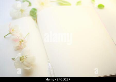 Open book with blank sheets and a pen in apple blossoms around. Inspiration concept to create or write in spring mood Stock Photo