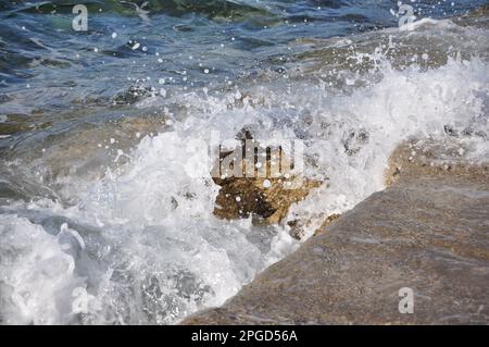 Water flowing from a waterfall. Water flowing over rocks.Wave breaking on the beach. Breaking sea wave on the rocky coast Stock Photo