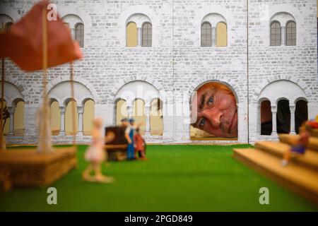 22 March 2023, Saxony-Anhalt, Magdeburg: Moritz Sostmann, director of the play 'The Dragon' looks through a gate of a model of the cloister and courtyard of the former monastery in which figures, a model stage and a model tribune can be seen at the Kunstmuseum Kloster Unser Lieben Frauen. The model illustrates the stage and tribune of the upcoming 'Hofspektakel' by the Magdeburg Puppet Theater, which will be performed this year in cooperation with the Unser Lieben Frauen Monastery Art Museum. The stage from the puppet theater will be located in the courtyard of the former monastery this season Stock Photo