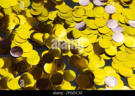 Lots of big round golden confetti close-up background. Fun party decoration confetti glittering and sparkling Stock Photo
