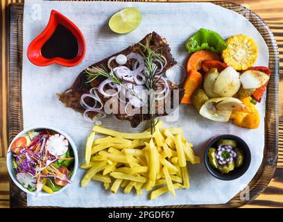 Grilled smoked pork ribs with french fries and soy sauce and salad on wooden board Stock Photo