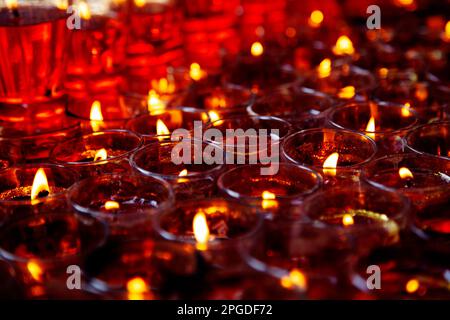 Close-up photo of a lot of red candles in glasses burning in a Chinese Taoist shrine at night. The flames of the candles create a sacred atmosphere fo Stock Photo