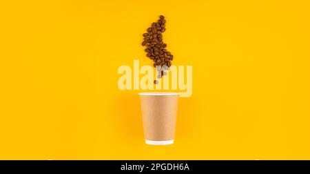 Paper coffee cup with beans in shape of coffee steam. Yellow background. Copy space Stock Photo