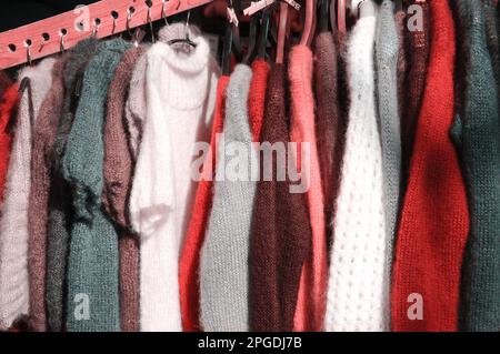 Stack of colorful  knitted colorful clothes - sweaters, dresses, cardigans etc.Toned photo Stock Photo