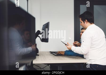 Side view of two colleagues working on a project together developing a new code  Stock Photo