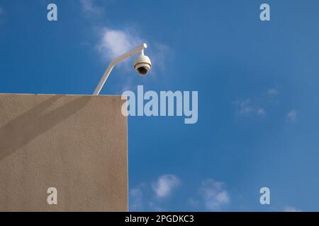 Surveillance camera on top of building with bright blue sky in background and copy space. Stock Photo