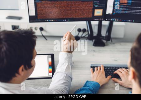 Over the shoulder close up view two programmers developing new app at work Stock Photo