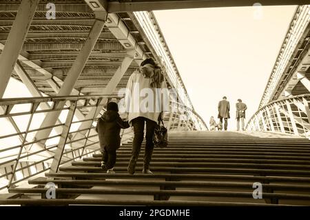 Mother and child (unidentified; back view) on Solferino bridge over Seine River. Paris, France. Single mom social and psychological problems issues Stock Photo