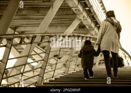 Mother and child (unidentified; back view) on Solferino bridge over Seine River. Paris, France. Single mom social and psychological problems issues Stock Photo