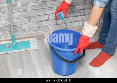 man pouring detergent into a bucket of water. using detergent while cleaning the house. wet room cleaning Stock Photo