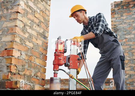 Uses blending drill. Construction worker in uniform and safety equipment have job on building Stock Photo