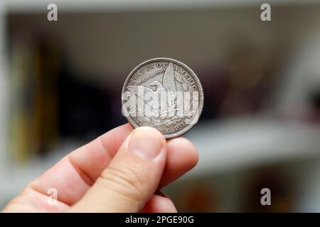 hand holding silver one dollar coin - Morgan Dollar Stock Photo