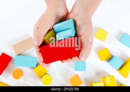 Child's hands playing with colorful wooden bricks. Wooden play set. Development and learning concept. Close-up view Stock Photo