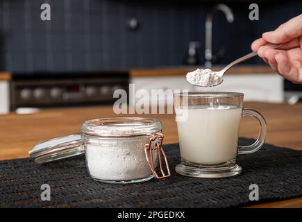 Diatomaceous earth also known as diatomite mixed in glass of water, good for human body detox concept. Jar and glass with healthy drink on home. Stock Photo