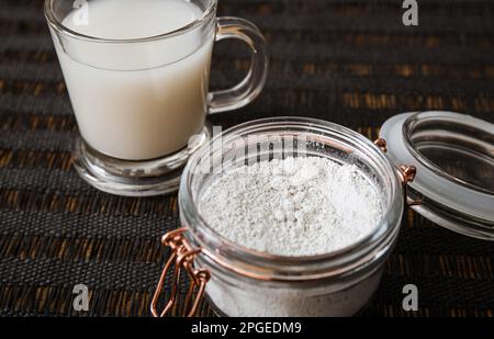 Diatomaceous earth also known as diatomite mixed in glass of water, good for human body detox concept. Jar and glass with healthy drink on home. Stock Photo