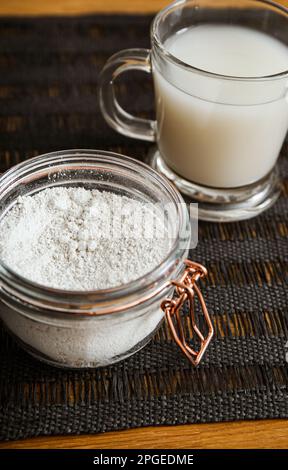 Diatomaceous earth also known as diatomite mixed in glass of water, good for human body detox concept. Jar and glass with healthy drink on home. Stock Photo