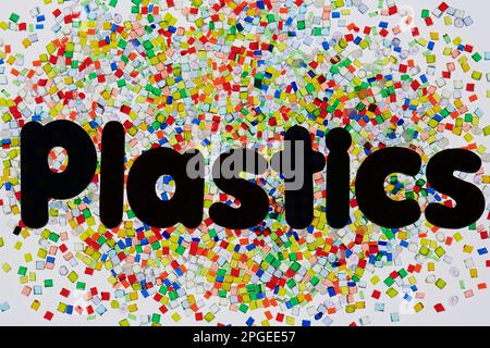 dumped heap of multicolored plastic resin granulates on white background with font letters Plastic Stock Photo