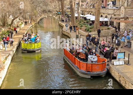 San Antonio, Texas, USA - February 2023: Aerial view of visitors on river boats which sail alongside the Riverwalk through the city centre Stock Photo