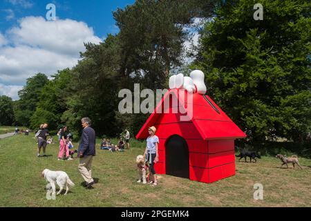 People taking selfies with their dogs standing in front of a massive red kennel with Snoopy lying on top at Goodwoof, The Kennels, Goodwood,Sussex, UK Stock Photo
