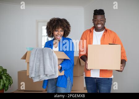 Moving Concept. Portrait Of Joyful Black Couple With Cardboard Boxes In Hands Stock Photo