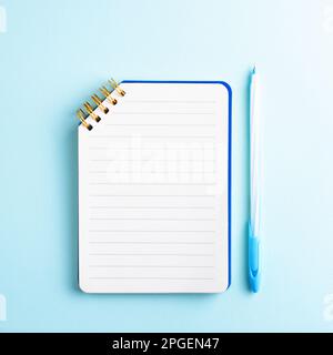 Open notebook with blank page and blue pen on blue background. Minimal composition, copyspace, education concept. Stock Photo