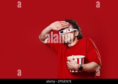 scared man in 3d-glasses holding bucket of popcorn Stock Photo