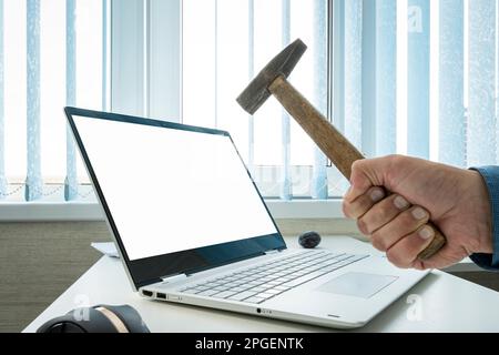 empty blank laptop screen for design or text message. copy space. Businessman breaks a laptop with an empty white screen with a hammer Stock Photo