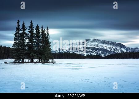 Dramatic view of Two Jack Lake with Mount Rundle and pine forest in winter on the evening at Banff national park, Alberta, Canada Stock Photo