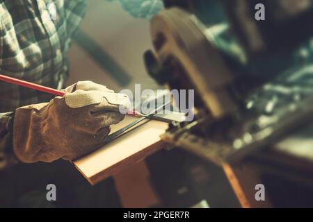 Man Measuring and Marking Piece of Wood Using Pencil To Cut Inside His Workshop. Close Up Photo. Stock Photo