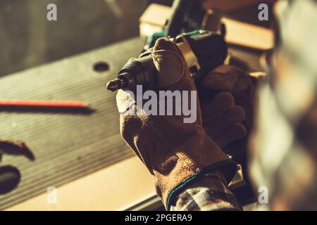 Construction Worker with Cordless Drill Driver and Wood Boring Drill Bit Attached Close Up Photo. Stock Photo