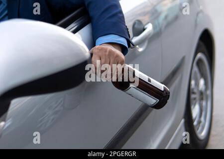 A man in an expensive suit drinks beer at the wheel of a car causing the danger of an emergency. driver throws the bottle out of the car window. Drunk Stock Photo