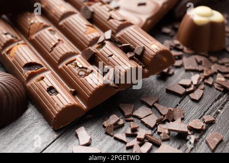 Broken handmade chocolate with chocolate chips and sweets on a dark background close-up. A bar of chocolate with raisins and nuts Stock Photo