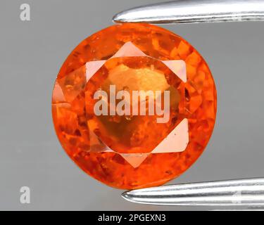 Natural gem orange hessonite garnet on gray background Stock Photo