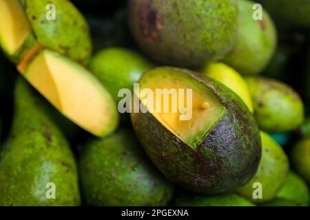 Fresh and ripe avocados, with pieces of flesh cut out to show the quality, are seen offered for sale in the street market in Ibagué, Colombia. Stock Photo