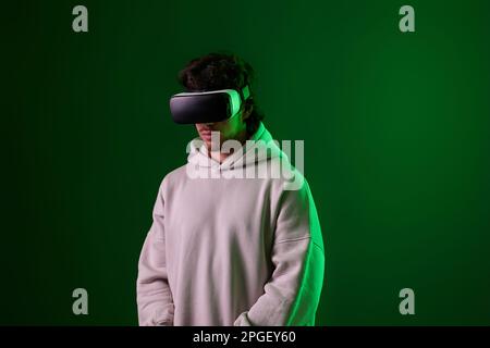 man in vr glasses and sweatshirt plays on blue background. Stock Photo