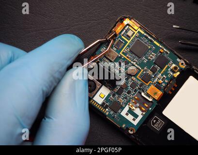 Repairing inside of mobile phone. Smart phone circuit board. High technology device maintenance engineering. Stock Photo