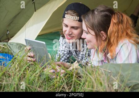 Young couple using digital tablet in camp tent, Bavaria, Germany Stock Photo