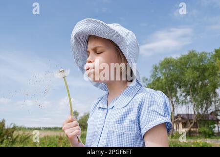 Portrait of a girl blowing on a dandelion. Stock Photo